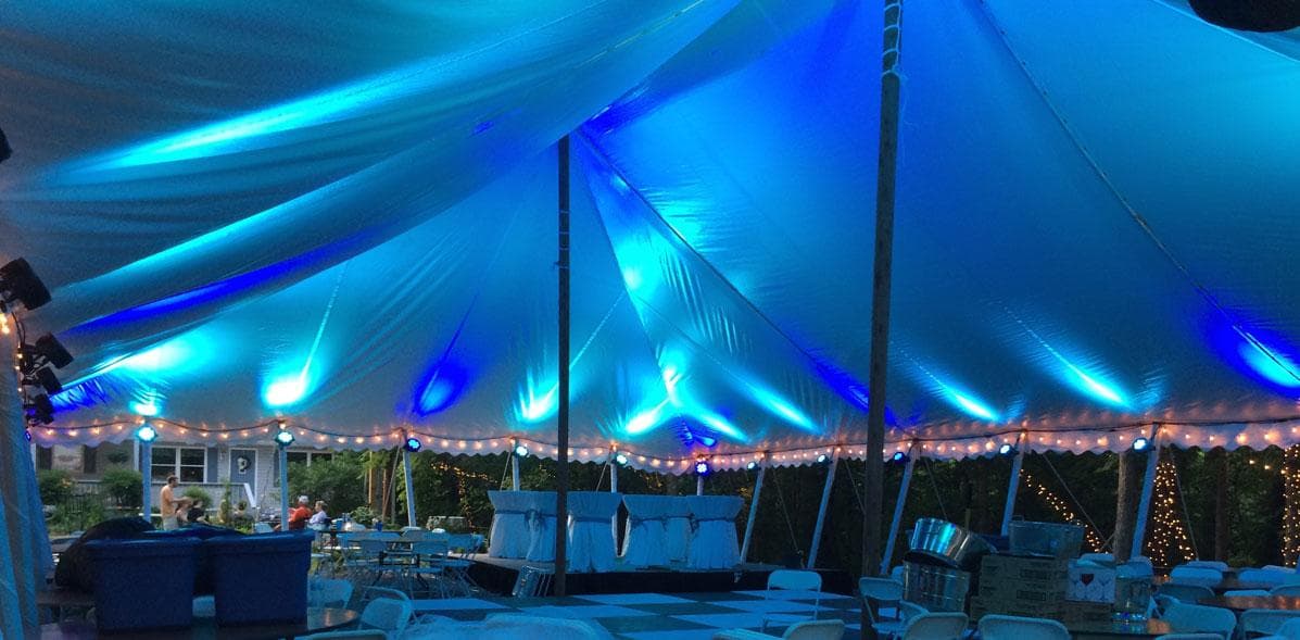 Event tent with tables and seating lit by cyan uplighting
